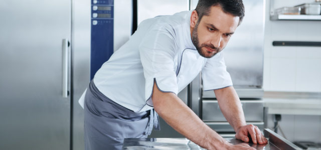 young professional cook cleaning commercial kitchen