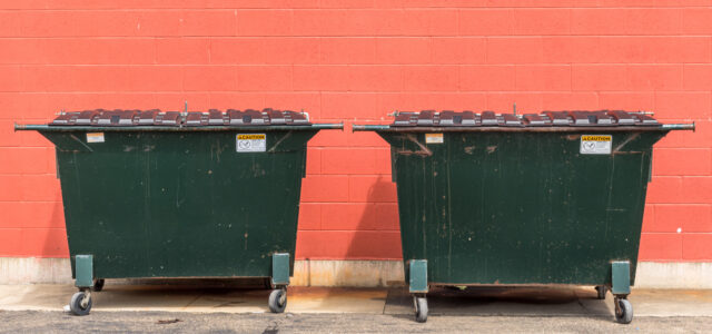 two dumpsters against a wall